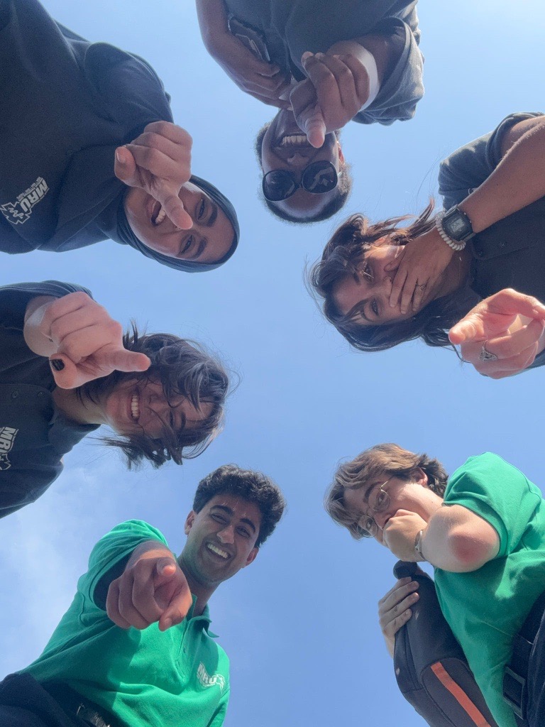 Selfie taken with MRU, everyone is in a circle with the phone pointed straight up and MRU memembers looking down at camera